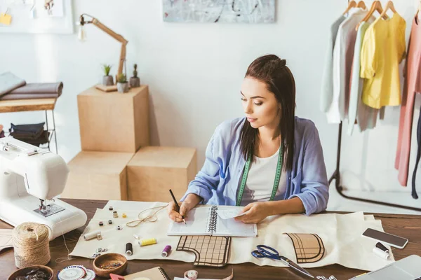 Seamstress writing down notes to notebook — Stock Photo