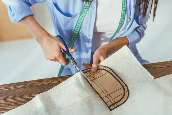 Abgeschnittenes Bild einer Näherin, die Stoff mit der Schere schneidet — Stock Photo