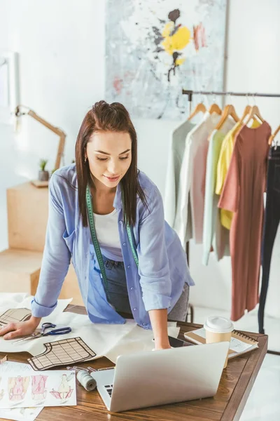 Näherin steht am Arbeitsplatz und schaut auf Laptop — Stockfoto