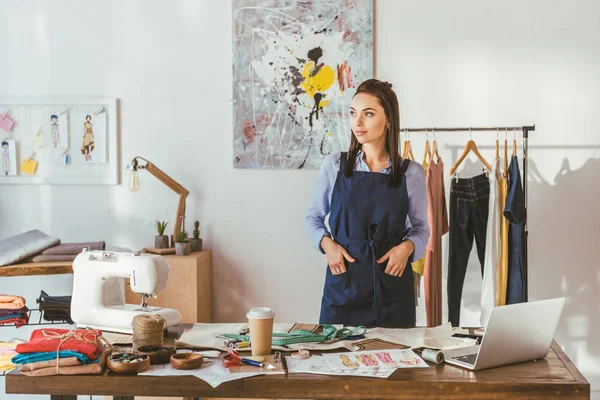 Young seamstress standing at working place and looking away — Stock Photo