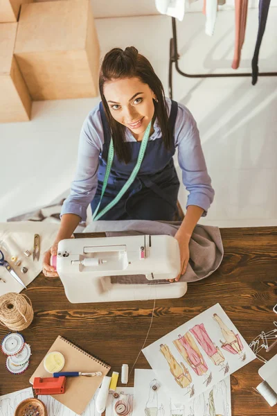 Overhead view of cheerful seamstress sewing cloth — Stock Photo