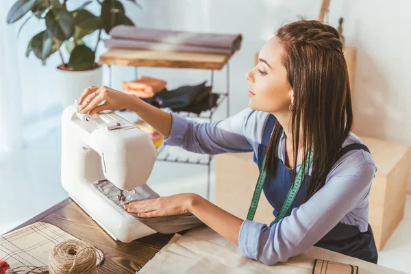 Attractive seamstress sewing with sewing machine — Stock Photo