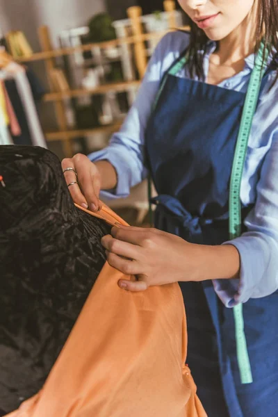 Cropped image of tailor making yellow dress on mannequin — Stock Photo