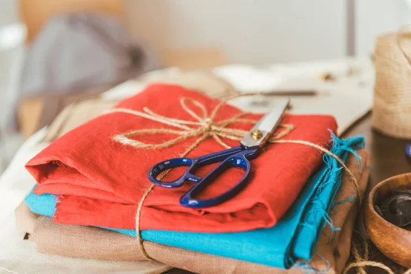 Stapel farbiger Stoffe und Scheren auf dem Tisch im Arbeitszimmer — Stockfoto