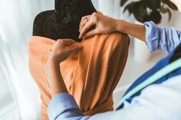 Cropped image of tailor putting pin into dress on mannequin — Stock Photo