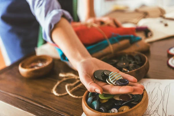 Imagen recortada de costurera sosteniendo botones en la mano - foto de stock