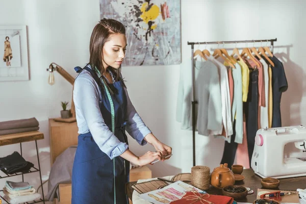 Seamstress taking photo of sketches with smartphone — Stock Photo