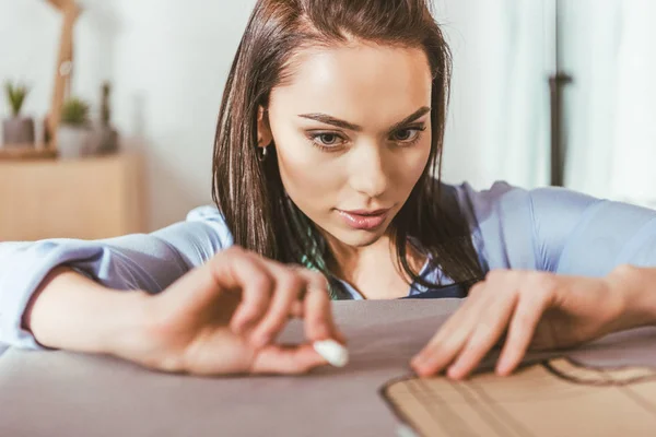Attractive seamstress making pattern with piece of chalk on fabric — Stock Photo