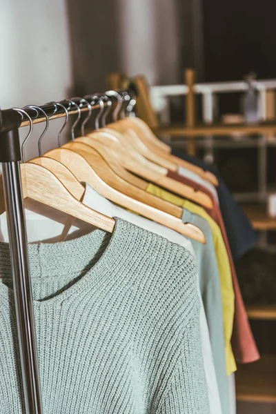 Linha de diferentes camisolas coloridas e camisas em cabides — Fotografia de Stock