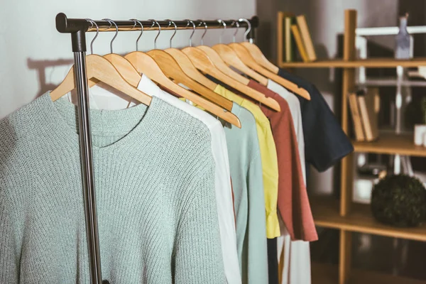 Camisolas coloridas diferentes e camisas em cabides — Fotografia de Stock