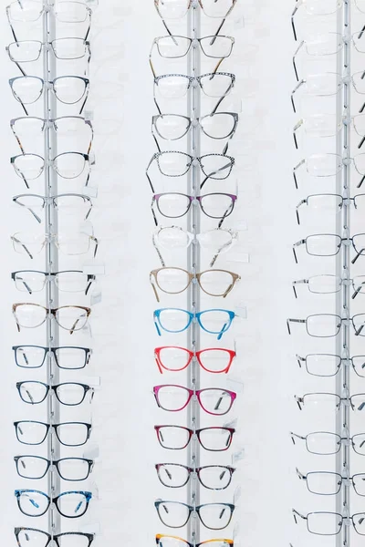 Fond avec différentes lunettes sur des étagères en optique — Photo de stock