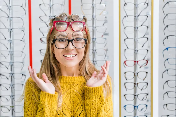 Молода здивована дівчина вибирає окуляри в оптиці — Stock Photo