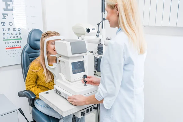 Ärztin untersucht Patientin durch Spaltlampe in Klinik — Stockfoto