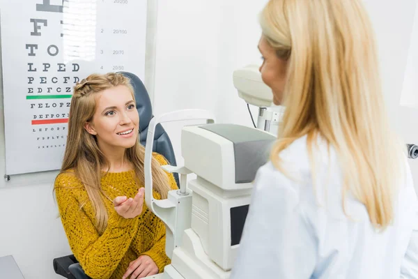 Optometrista profesional examinando paciente a través de lámpara de hendidura en clínica - foto de stock