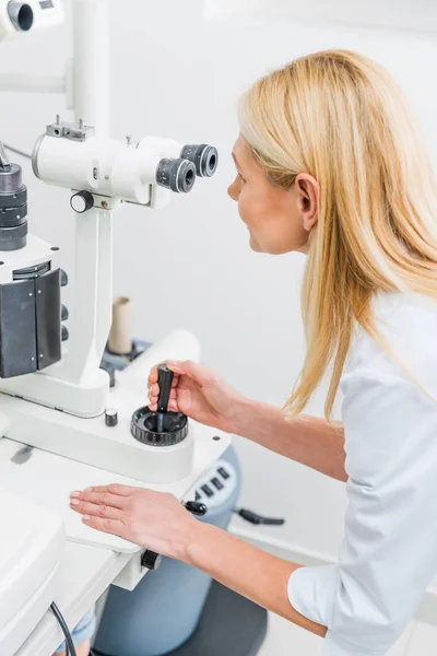 Professional optician working with slit lamp in clinic — Stock Photo