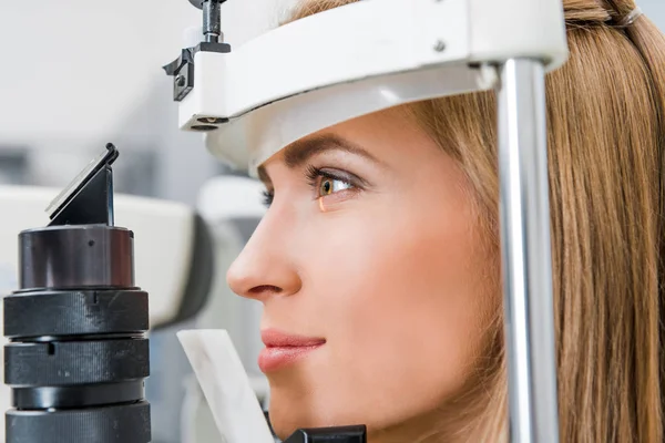 Nahaufnahme einer attraktiven Patientin, die ihre Augen mit Spaltlampe in der Klinik untersucht — Stockfoto