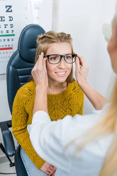 Окулист и пациент пробует новые очки в клинике — стоковое фото