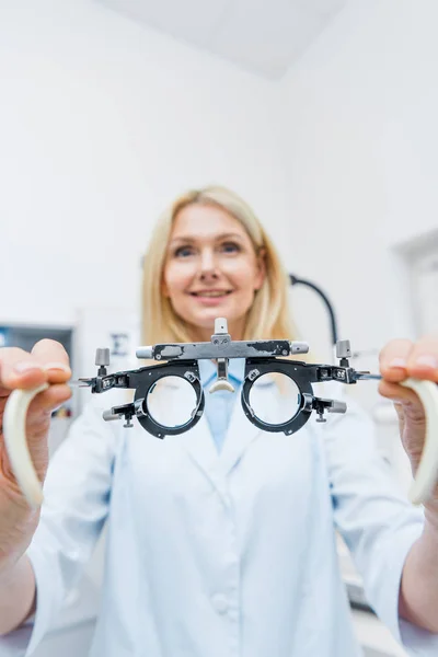 Optician no revestimento branco que prende o quadro experimental na clínica — Fotografia de Stock