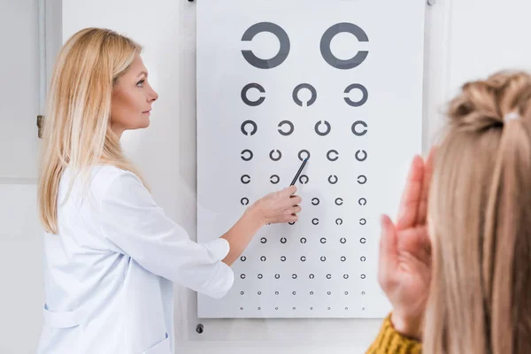 Пациент и оптик делает глазной тест с диаграммой в клинике — стоковое фото