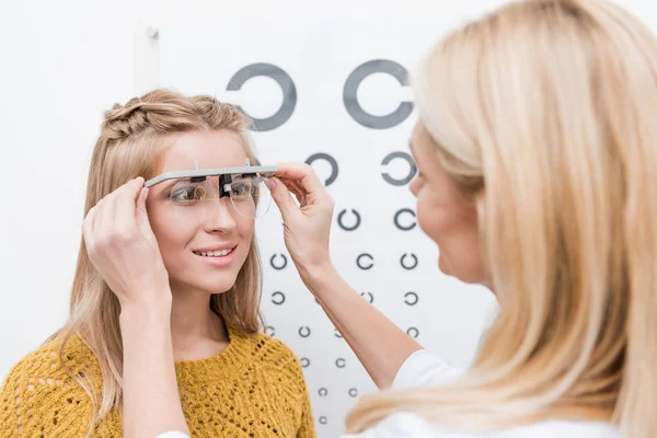 Patient et oculiste avec cadre d'essai et tableau oculaire derrière — Photo de stock