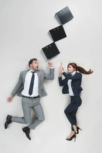 Overhead view of shocked businesspeople in suits and folders isolated on grey — Stock Photo