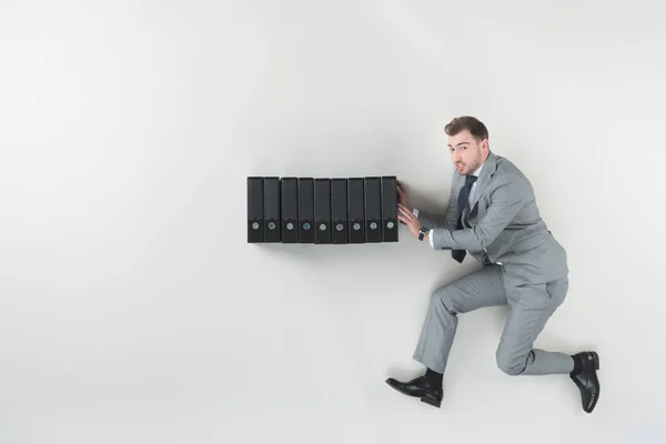 Overhead view of businessman pushing folders isolated on grey — Stock Photo