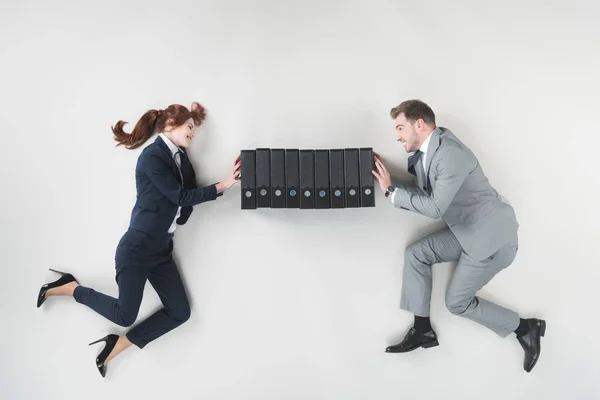 Overhead view of smiling businesspeople pushing folders isolated on grey — Stock Photo