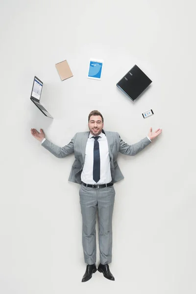 Blick über den Kopf eines lächelnden Geschäftsmannes mit ausgestreckten Armen und Büromaterial über dem Kopf, der isoliert in die Kamera auf grau blickt — Stockfoto