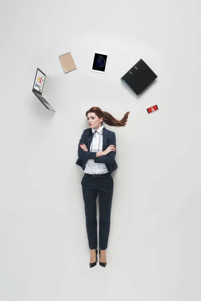 Vista aérea de la mujer de negocios con varios suministros de oficina por encima de la cabeza aislado en gris - foto de stock
