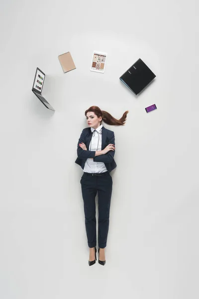 Vue aérienne de femme d'affaires avec divers fournitures de bureau au-dessus de la tête isolé sur gris — Photo de stock