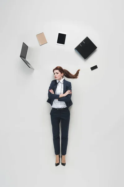 Vue aérienne de femme d'affaires avec divers fournitures de bureau au-dessus de la tête isolé sur gris — Photo de stock