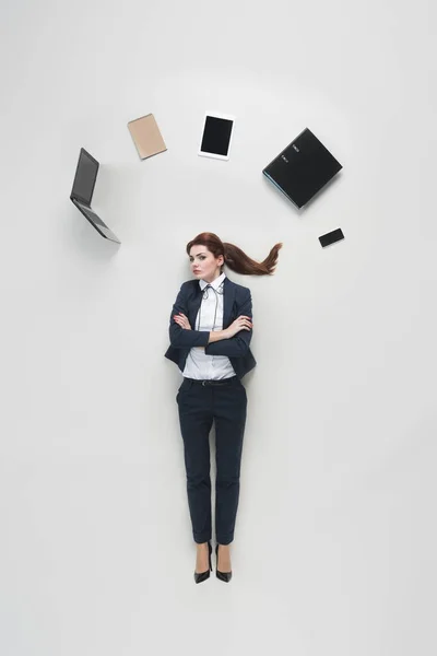 Vista aérea de la mujer de negocios con varios suministros de oficina por encima de la cabeza aislado en gris - foto de stock