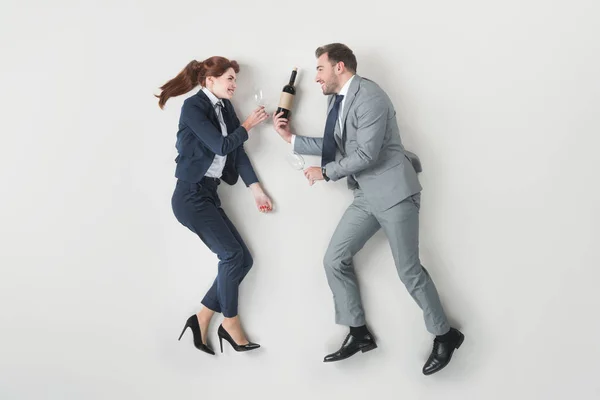 Overhead view of smiling business colleagues with bottle of wine and wine glasses isolated on grey — Stock Photo