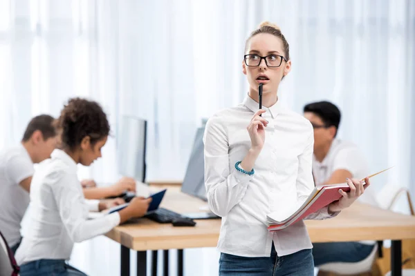 Joven pensativo caucásico estudiante chica en aula con amigos - foto de stock