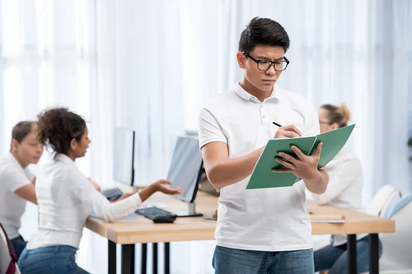 Jeune asiatique étudiant garçon écriture sur exercise book — Photo de stock