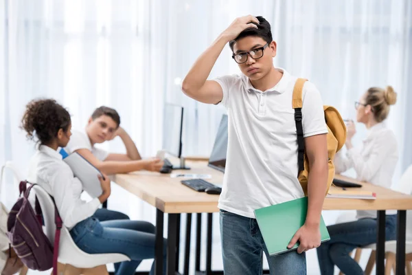 Young pensive asian student boy in classroom with friends — Stock Photo