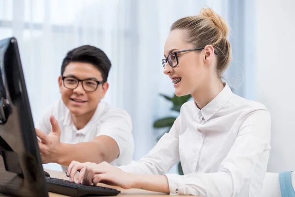 Young happy students pointing on screen of computer — Stock Photo