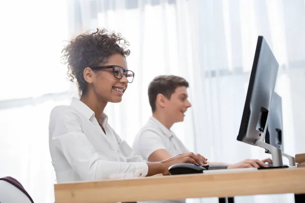 Heureux jeunes étudiants travaillant sur des ordinateurs — Photo de stock