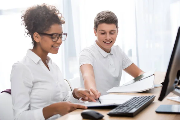 Happy students writing on exercise book — Stock Photo