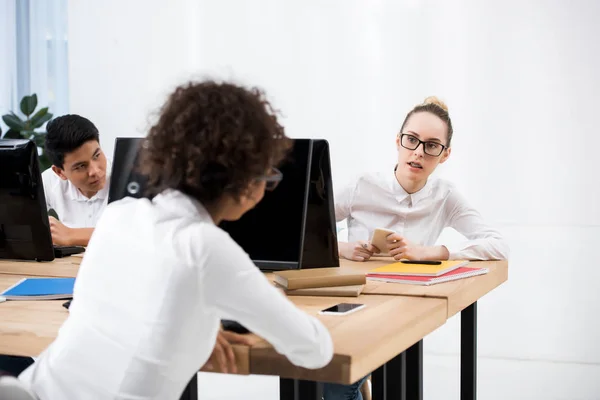 Adolescentes étudiantes assises à table et se regardant — Photo de stock