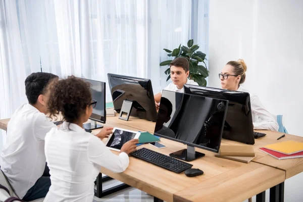 Four young multicultural students studying on computers — Stock Photo