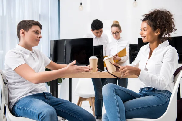 Young multicultural teen students studying together and holding cups with coffee — Stock Photo