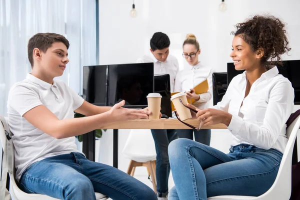 Jovem multicultural adolescente estudantes estudando juntos e segurando copos com café — Fotografia de Stock