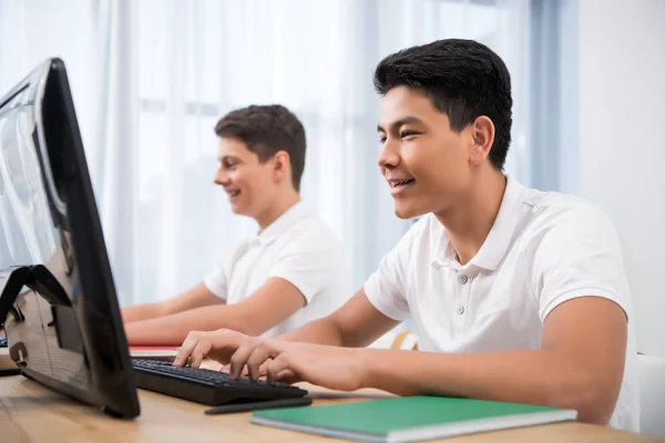 Joven feliz adolescente chicos estudiando en computadoras - foto de stock