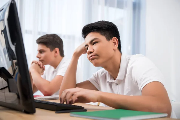 Jovens adolescentes cansados estudando em computadores — Fotografia de Stock