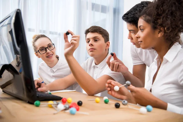 Jeunes étudiants multiculturels choisissant un modèle moléculaire pour une leçon de science — Photo de stock