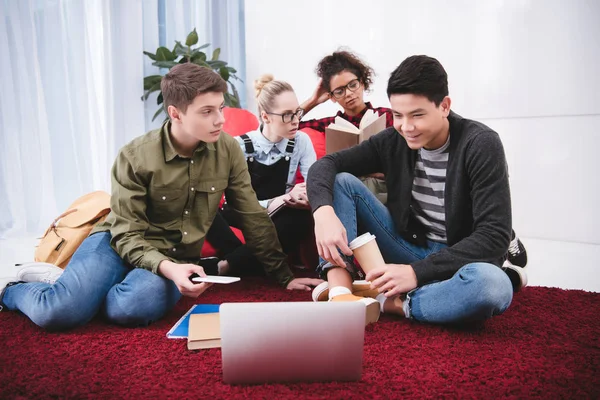 Multicultural teenagers studying with laptop and exercise books — Stock Photo