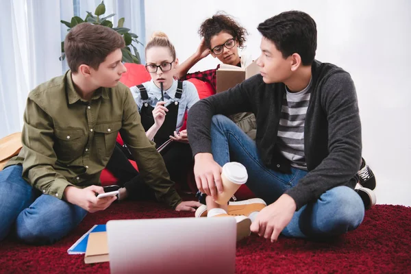 Multicultural teenagers studying with laptop and exercise books — Stock Photo