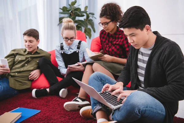 Multicultural teenagers studying with laptop and exercise books — Stock Photo