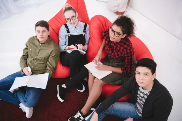 Fröhliche Schüler sitzen mit Schulheften — Stockfoto